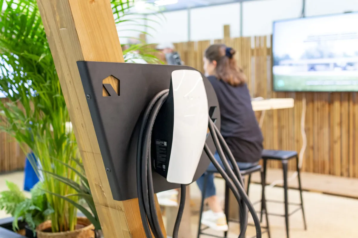Une borne de recharge pour voiture électrique fixée au poteau en bois d'un carport