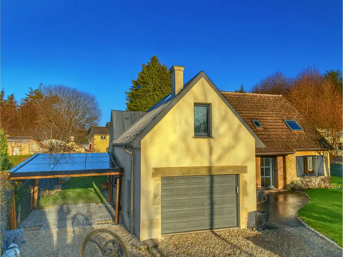 Un carport solaire en bois accolé à une maison aux murs jaunes, sous un ciel bleu