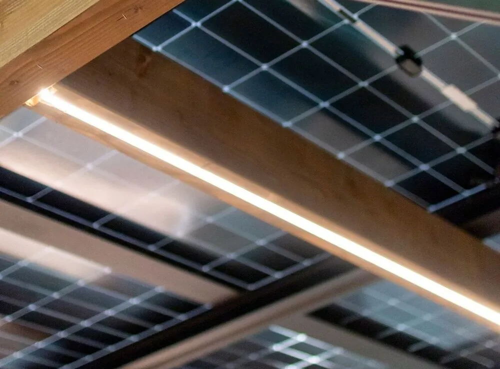 Les panneaux solaires vus de dessous, avec le bandeau LED intégré à la charpente en bois